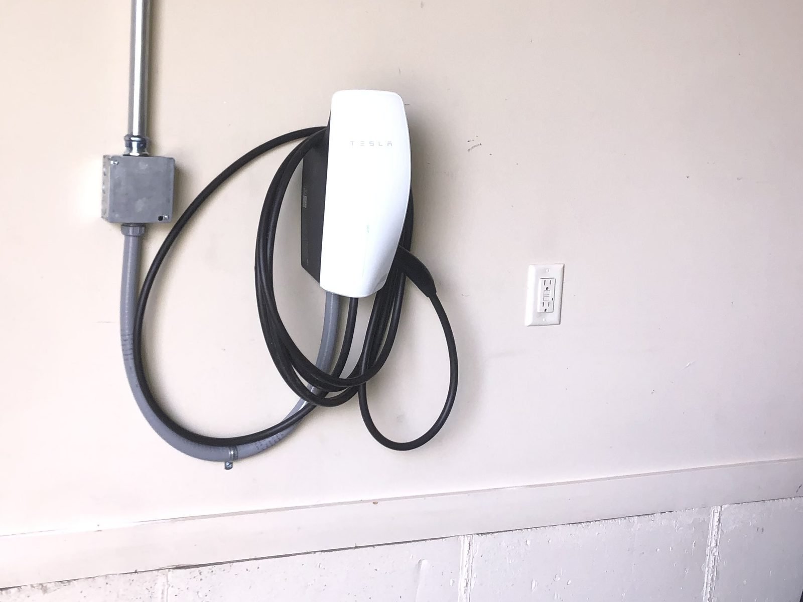 Tesla Wall Connector hardwired through a junction box and flexible conduit in a garage